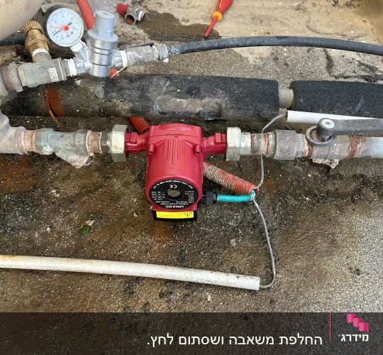 משאבה אדומה וצנרת על רצפה רטובה